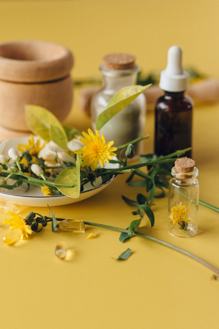 Dried herbs and essential oils on a yellow background, perfect for natural health concepts.
